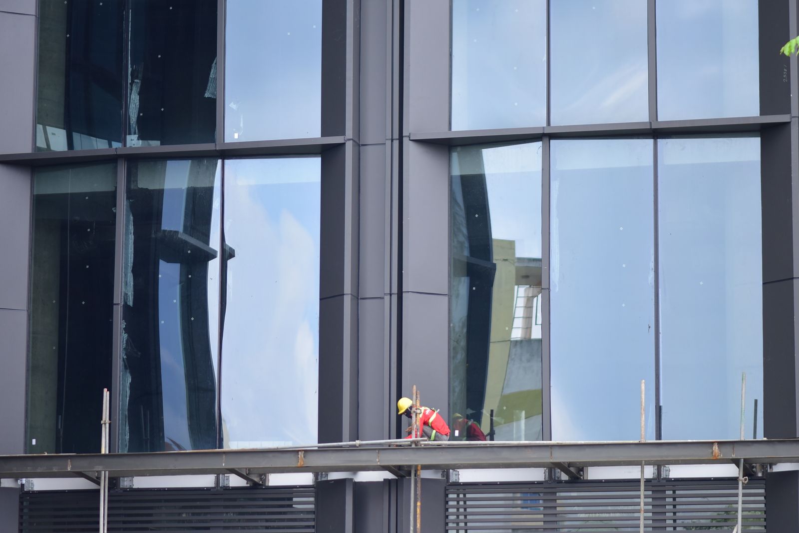 Trabajador interviniendo la fachada de un edificio contemporáneo